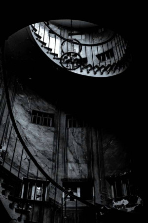 Black and white image of a spiral staircase inside a stone building.