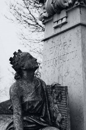 Black and white photograph of a sculpted woman in mourning, with the word 'Evora' inscribed on a monument.