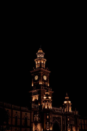 A tall clock tower illuminated against a dark night sky.