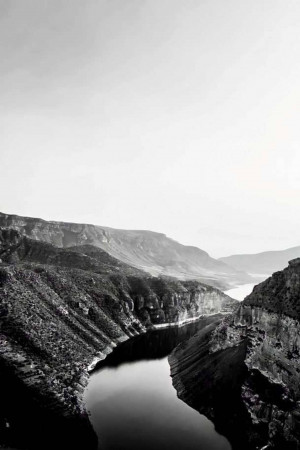 Black and white photograph of a winding river through a deep canyon.