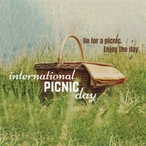 Wicker picnic basket in a grassy field with text overlay promoting International Picnic Day
