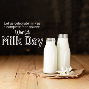 Two bottles of milk with a flower on a wooden surface celebrating World Milk Day