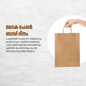 A hand holding a brown paper shopping bag with Malayalam text in the background.