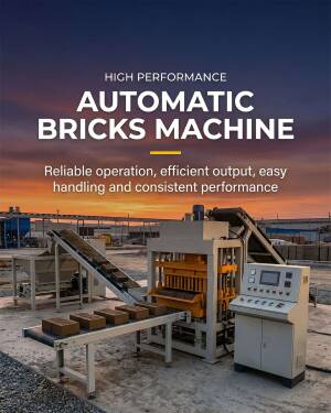 An industrial automatic brick making machine operating in an outdoor factory yard at sunset.