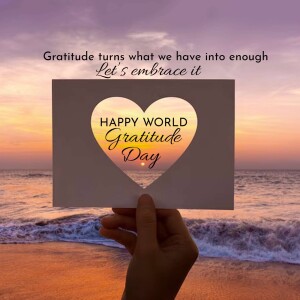 Hand holding a card with a heart shape and the text 'Happy World Gratitude Day' against a sunset beach background.