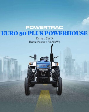 Blue Powertrac Euro 50 Plus tractor on a road with a city skyline in the background