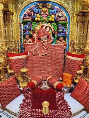 Close-up of a vibrant Hanuman idol adorned with flowers and textiles in a richly decorated temple.