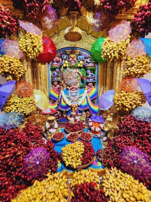A vibrant and colorful depiction of Hanuman Ji adorned with fruits and umbrellas.