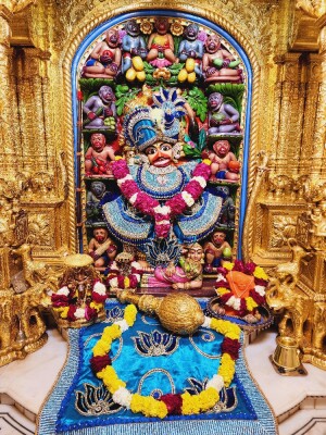 Intricate golden shrine of Lord Hanuman adorned with flowers and offerings.