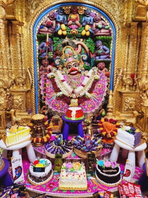 Close-up of a beautifully decorated Hanuman idol with offerings of cakes and flowers.
