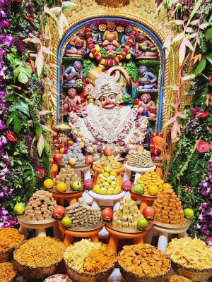 Close-up of a beautifully decorated Hanuman statue surrounded by colorful offerings of sweets and snacks.
