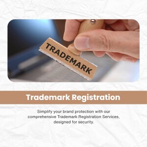 Hand stamping the word 'TRADEMARK' onto a document with a laptop in the background, promoting trademark registration services.
