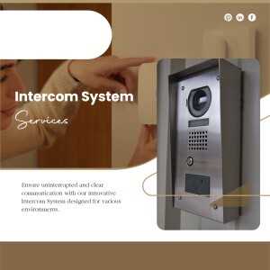 Close-up of an intercom system mounted on a wall with a hand pointing towards it.