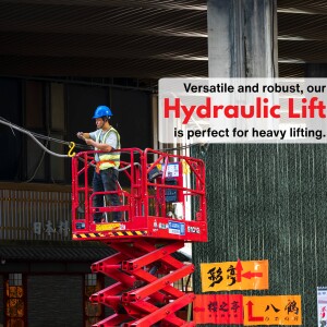 Worker operating a red hydraulic lift on a construction site.