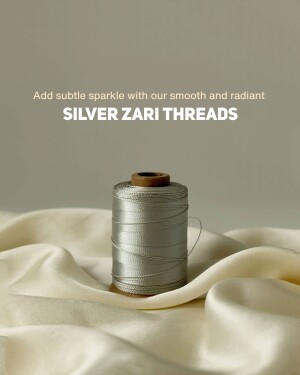 Close-up of a spool of silver zari thread on a silk fabric