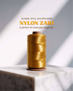 Close-up of a spool of golden nylon zari thread on a white marble surface.