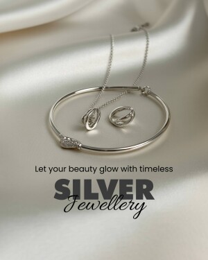 Silver necklace, bracelet, and earrings on a satin background
