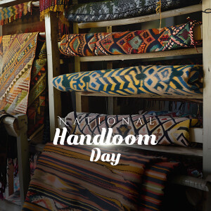 A display of colorful handwoven textiles and rugs in a shop, celebrating National Handloom Day.