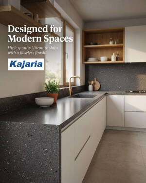 A modern kitchen interior featuring Kajaria Vitronite dark speckled countertops with white minimalist cabinets and wooden accents.