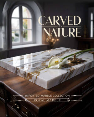 A slab of luxury white marble with golden veining sits on a wooden desk with a calla lily and brass accents.