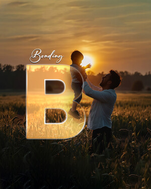 Father lifting son into the air at sunset with a large letter 'B' in the foreground.
