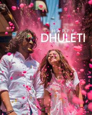 A joyful couple covered in colorful powder celebrating Dhulleti.
